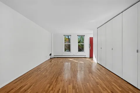 a view of an empty room with wooden floor and window