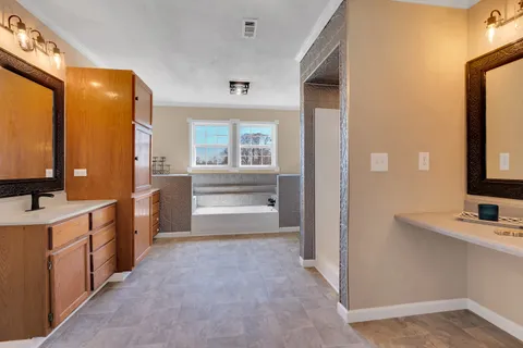 a bathroom with a double vanity sink a mirror and a bathtub