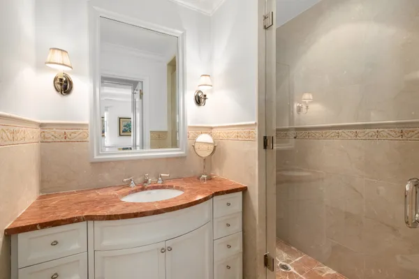 a bathroom with a granite countertop sink a mirror and shower