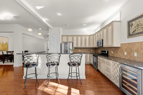 a kitchen with stainless steel appliances granite countertop a stove top oven a sink a dining table and chairs with wooden floor