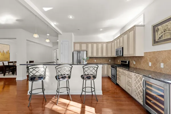 a kitchen with stainless steel appliances granite countertop a stove top oven a sink a dining table and chairs with wooden floor