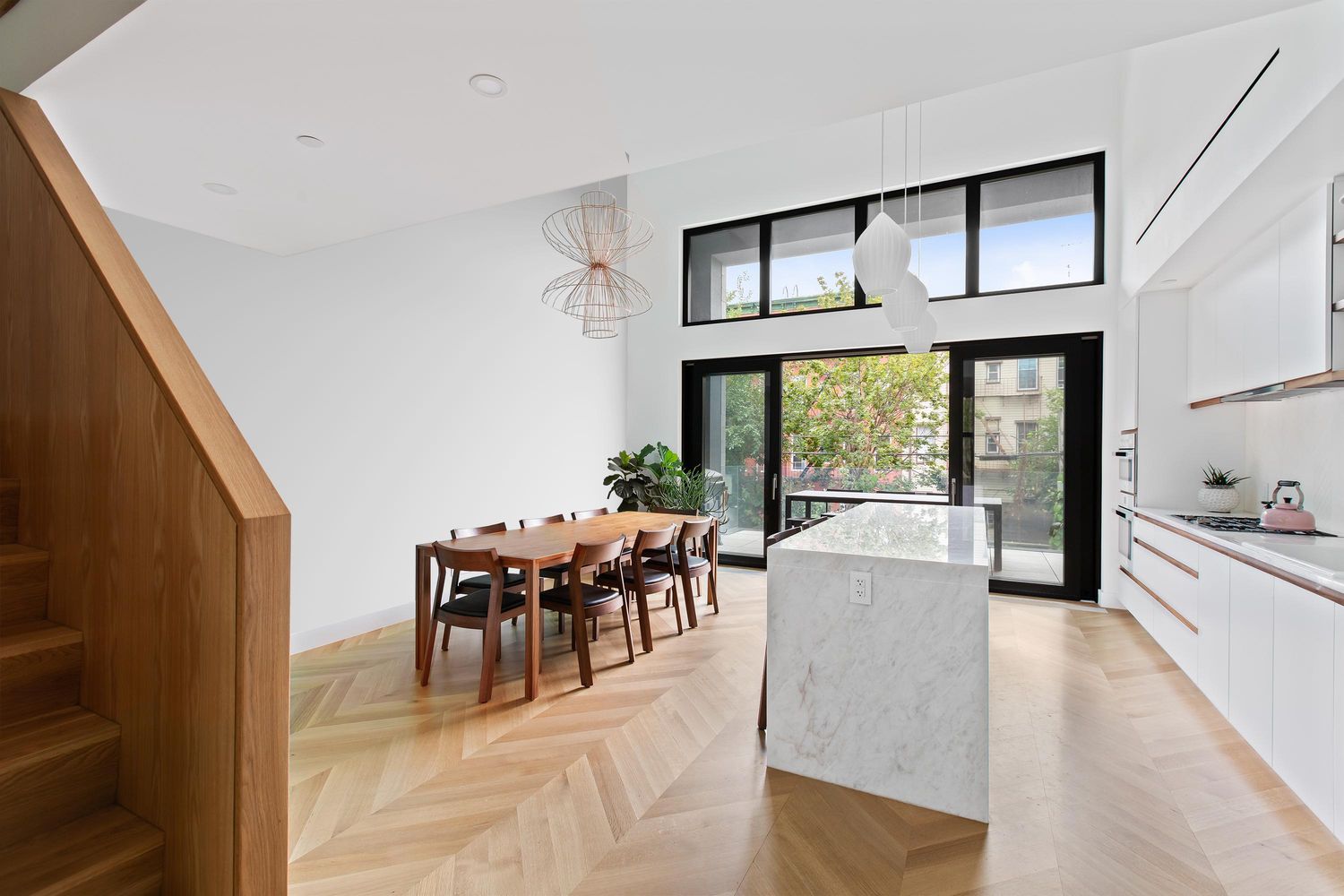 a dining room with wooden floor a chandelier a glass table and chairs