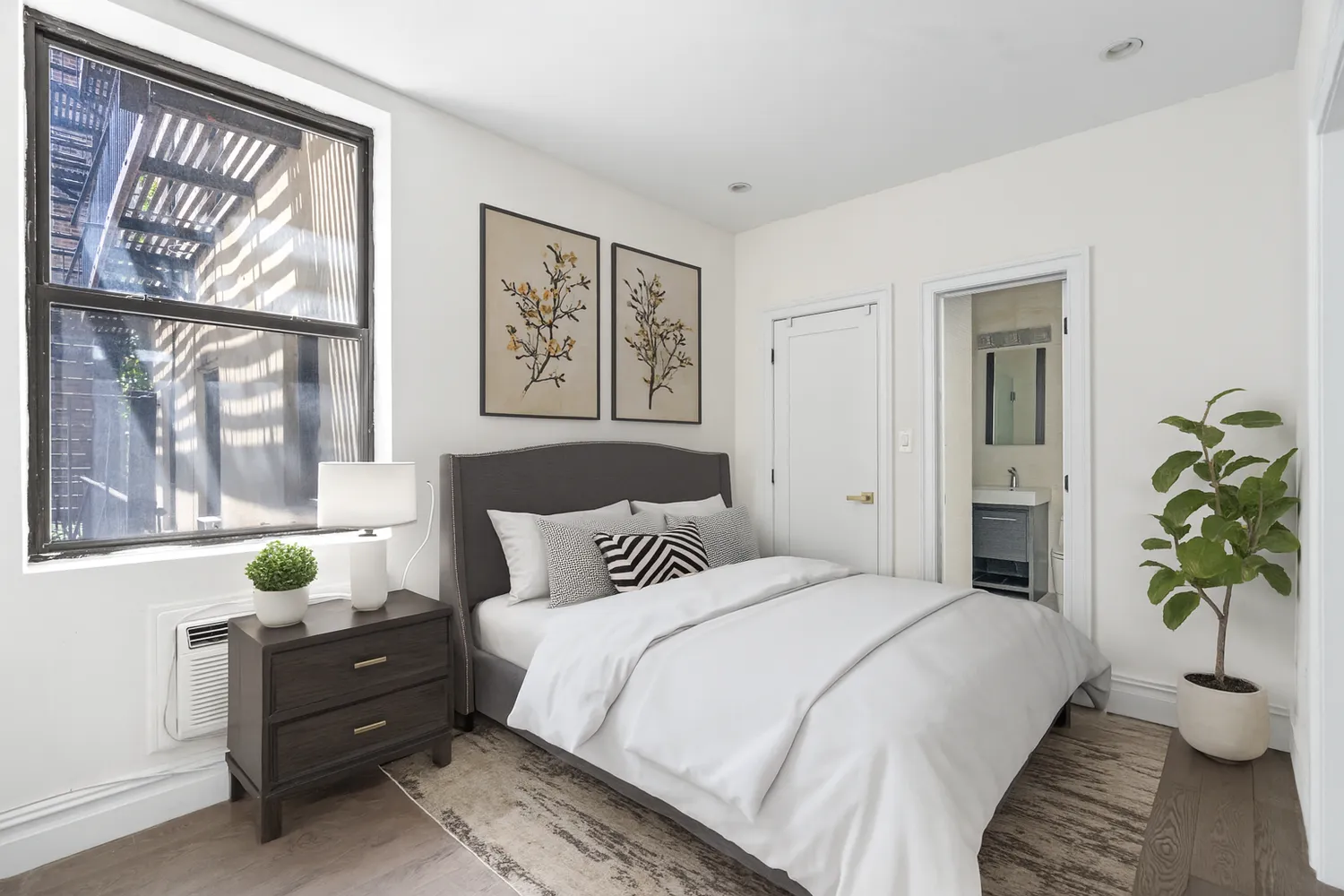 a bedroom with a bed and a window with potted plants