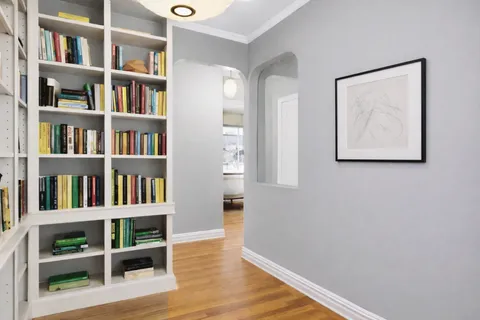 a view of a livingroom with bookshelf and wooden floor