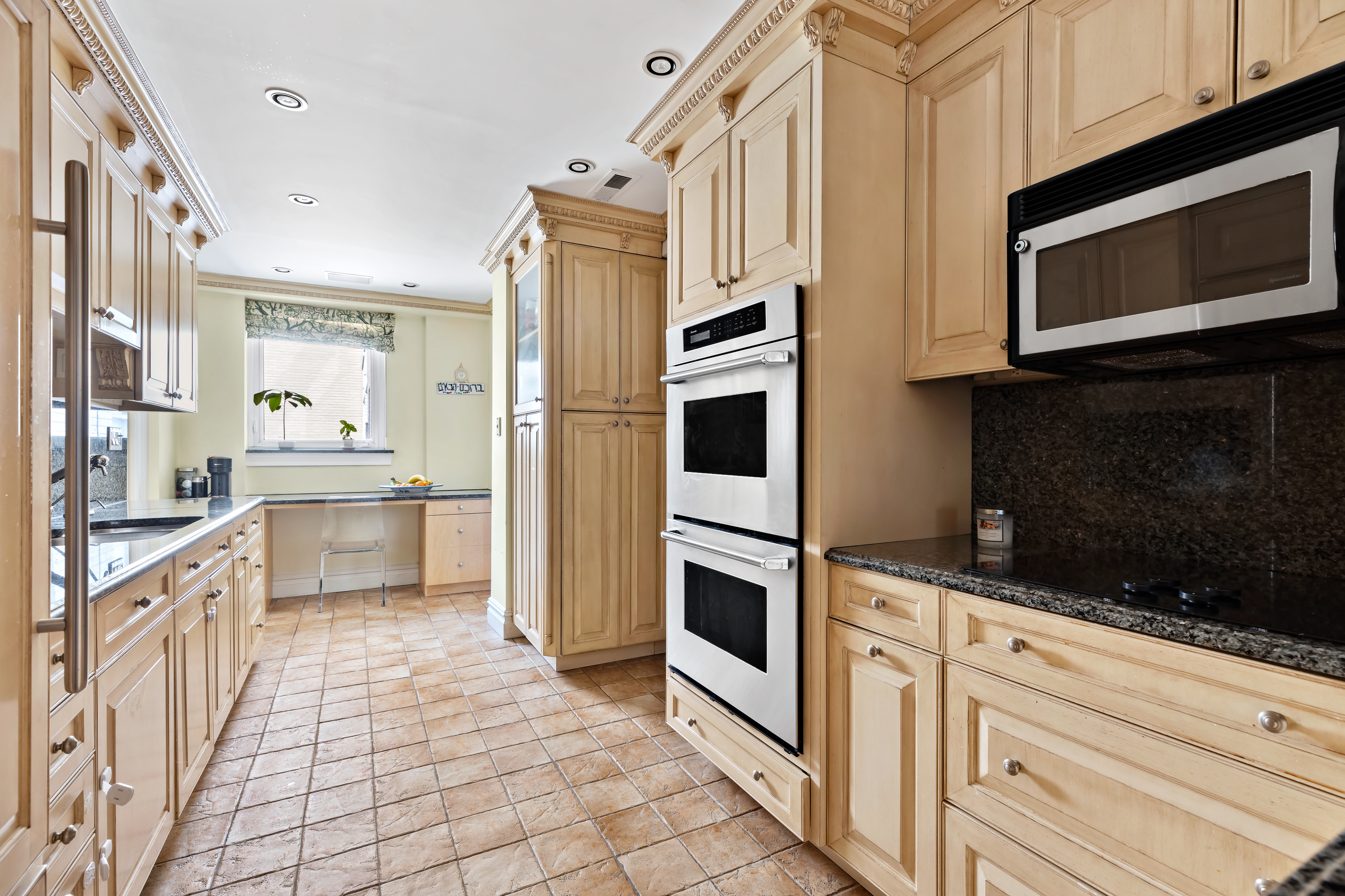 175 East 62nd Street, Unit 9D Manhattan, NY 10065 - Photo 4 of 12 a kitchen with stainless steel appliances a stove a microwave and cabinets