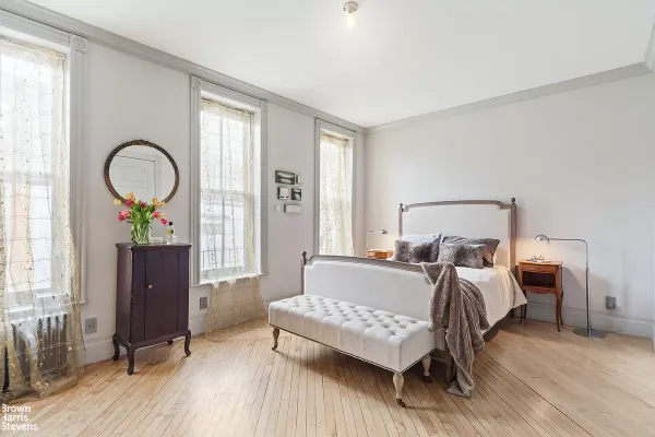 a bedroom with a bed and a wooden floor