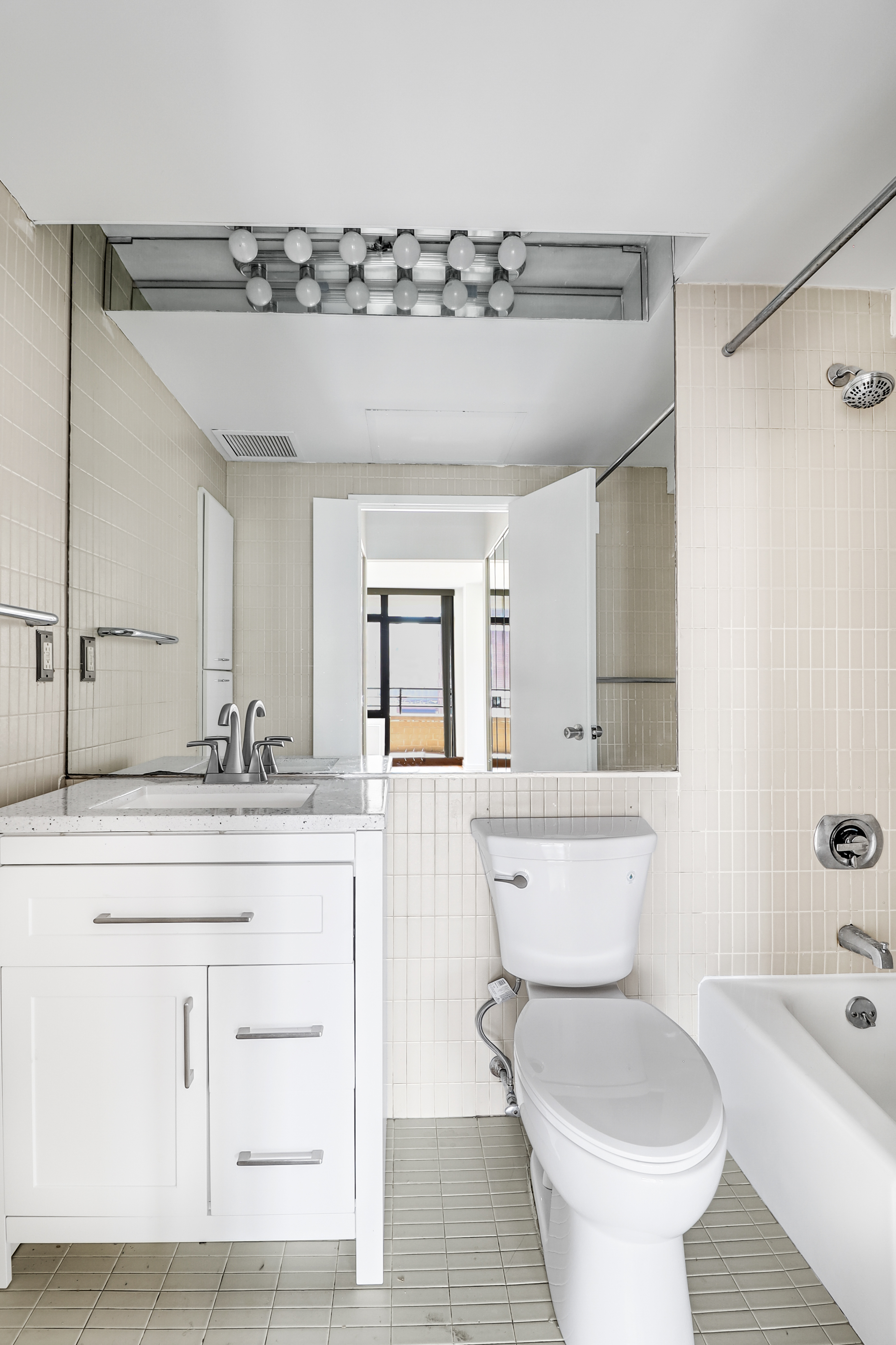 400 East 70th Street, Unit 1008 Manhattan, NY 10021 - Photo 8 of 15 a bathroom with a granite countertop sink mirror vanity and toilet