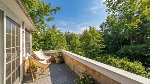 a balcony with wooden floor and yard in the back
