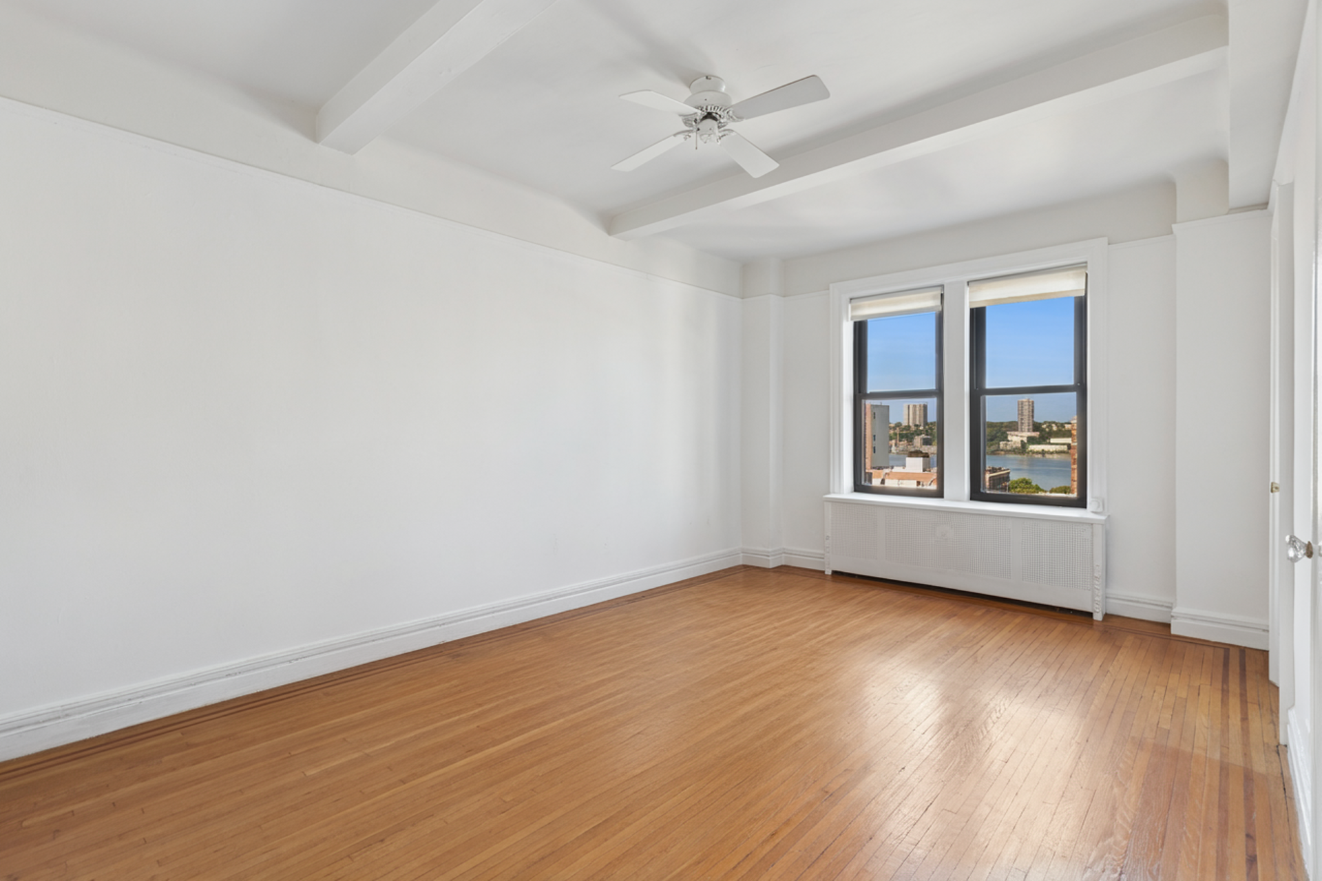 710 West End Avenue, Unit 14B Manhattan, NY 10025 - Photo 11 of 19 an empty room with wooden floor chandelier fan and windows