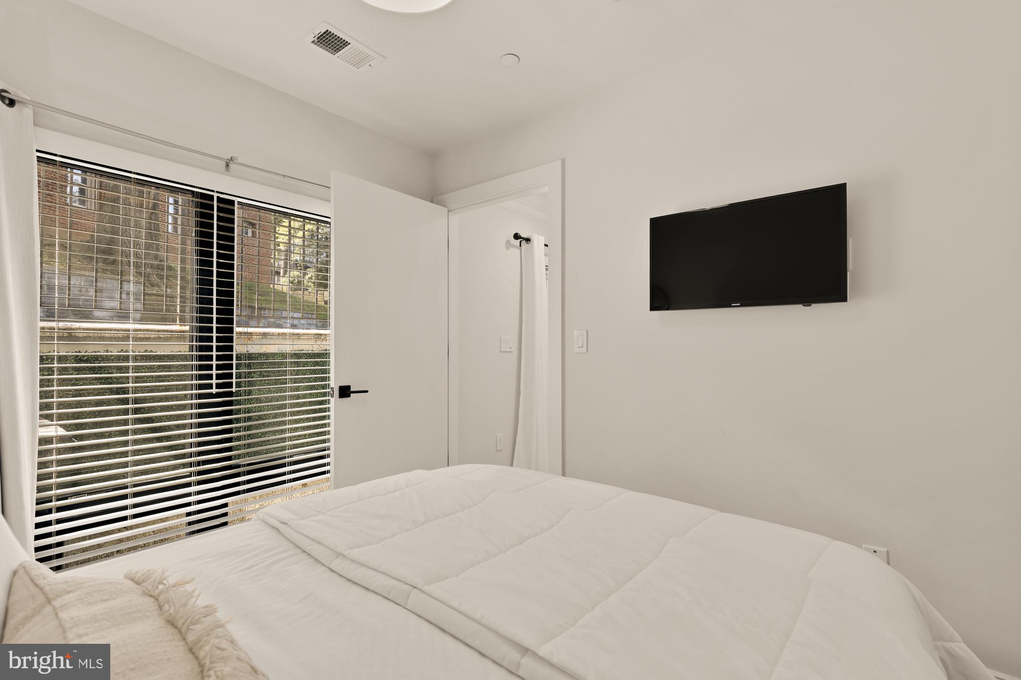 2630 39th Street Northwest, Unit 1 Washington, DC 20007 - Photo 17 of 26 a bedroom with a bed and a flat screen tv