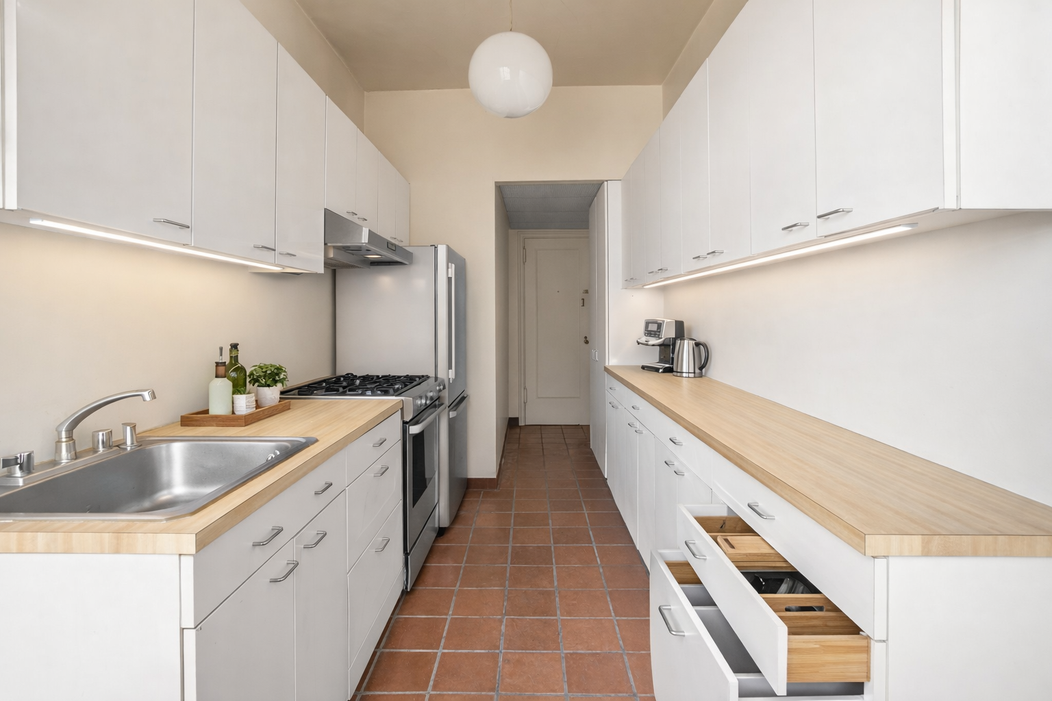 30 Sutton Place, Unit 12E Manhattan, NY 10022 - Photo 4 of 7 a large white kitchen with a sink and dishwasher a stove top oven with wooden floor