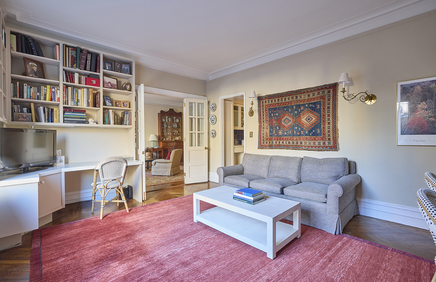 161 East 79th Street, Unit 7B Manhattan, NY 10075 - Photo 2 of 15 a living room with furniture and a book shelf with wooden floor