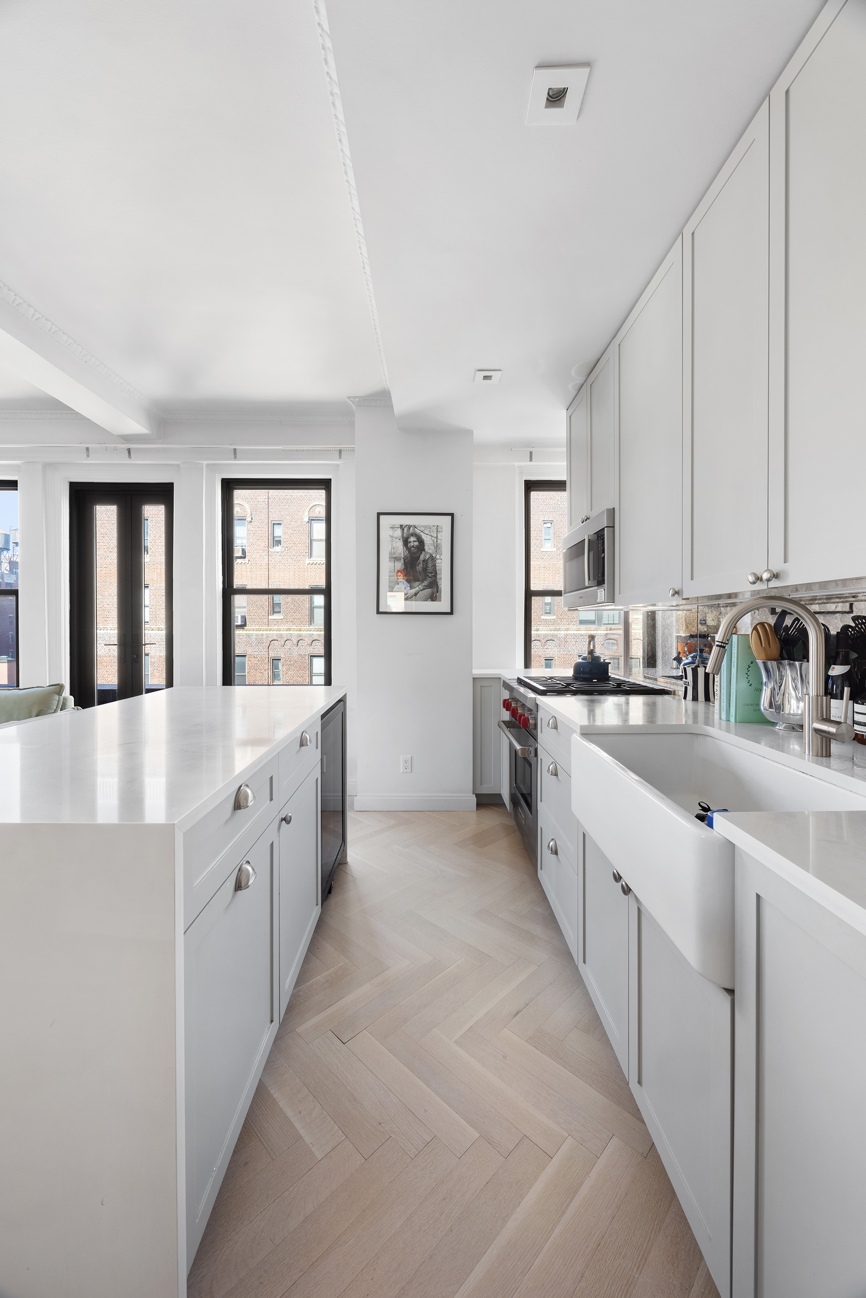 26 East 10th Street, Unit 11G Manhattan, NY 10003 - Photo 5 of 14 a large kitchen with kitchen island white cabinets and stainless steel appliances