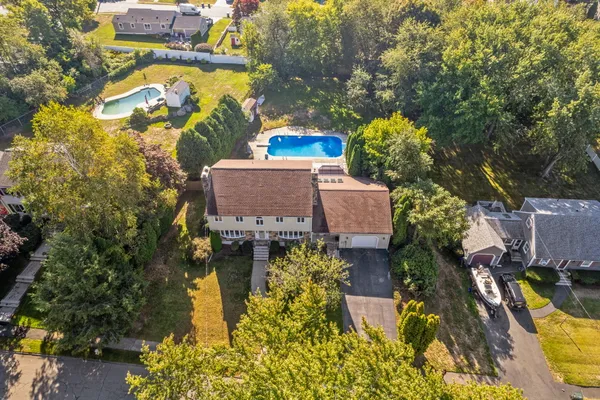 an aerial view of a house with swimming pool and large trees