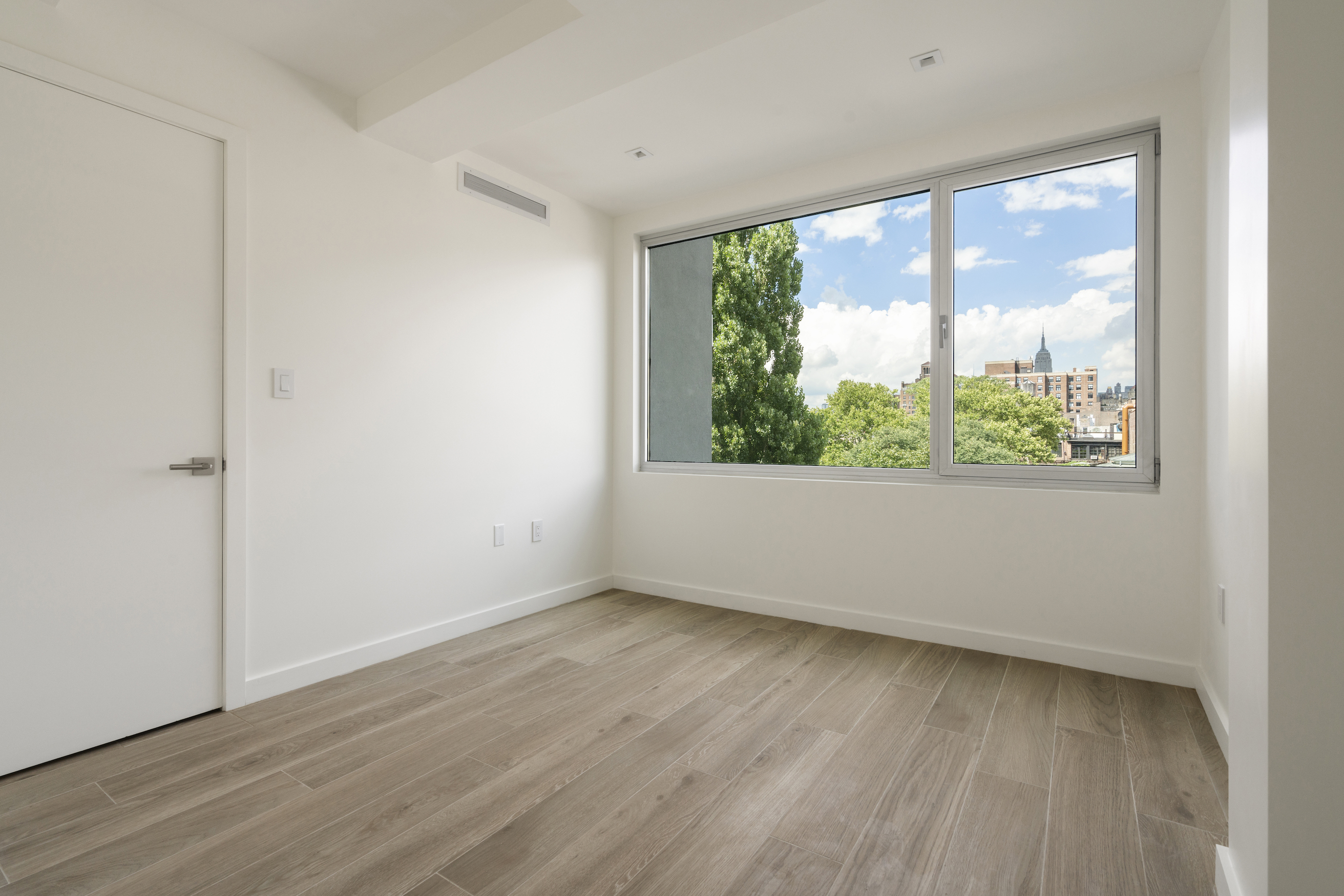 136 West Houston Street, Unit PH Manhattan, NY 10012 - Photo 22 of 26 a view of an empty room with wooden floor and a window