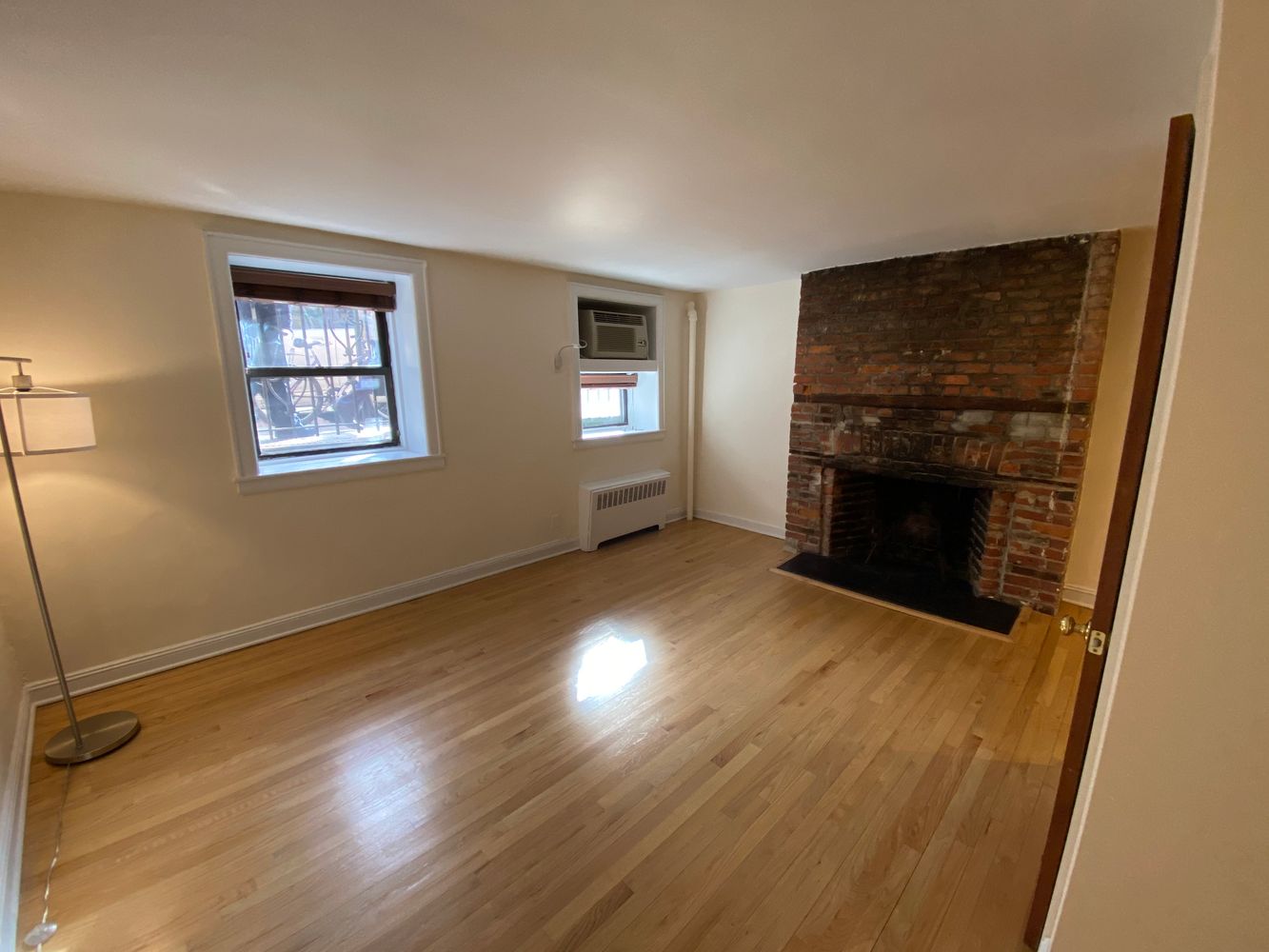 754 Greenwich Street, Unit 1A Manhattan, NY 10014 - Photo 3 of 6 an empty room with wooden floor fireplace and windows