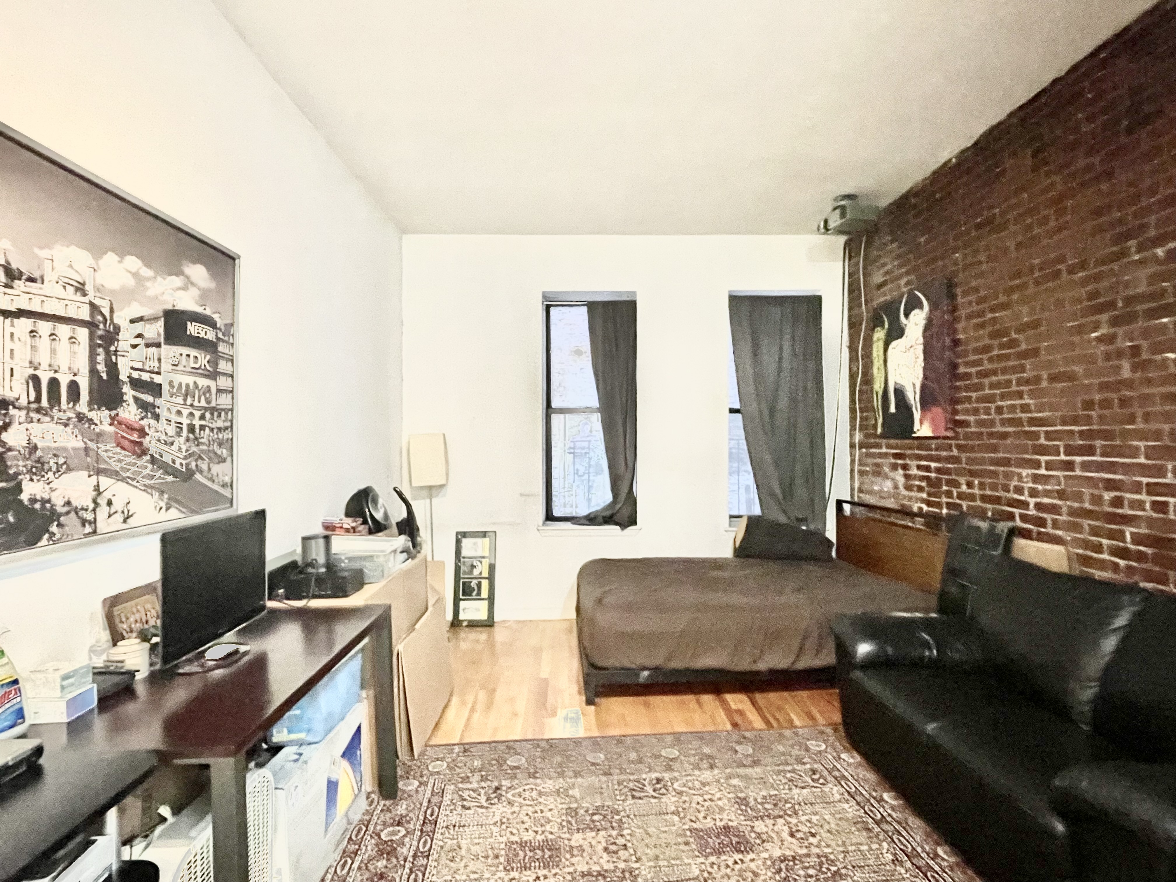 a living room with couches rug and a computer on the desk