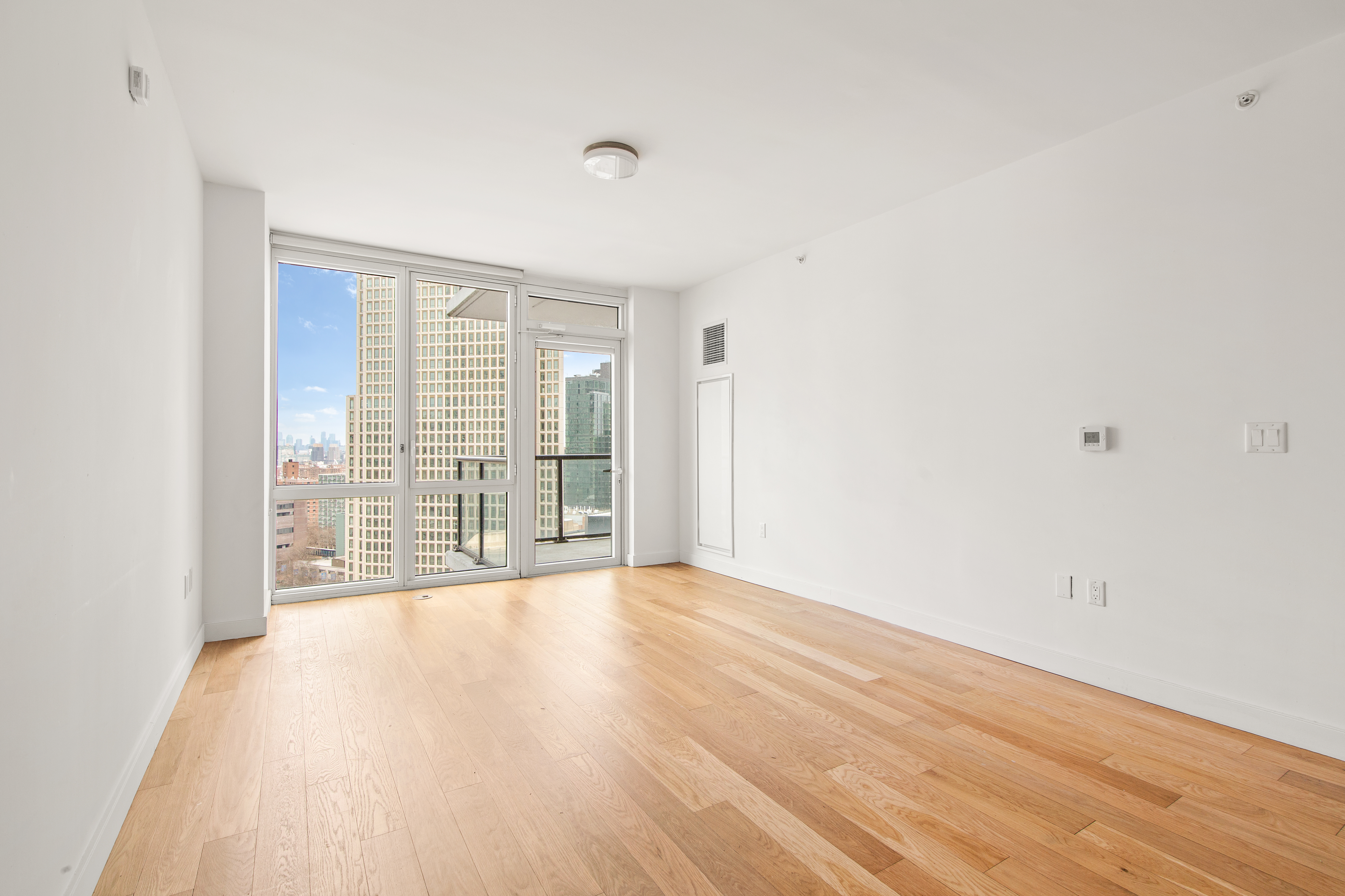 a view of an empty room with wooden floor and a window