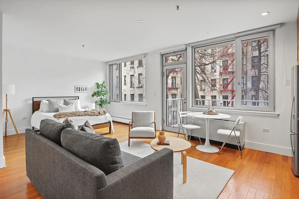 154 Attorney Street, Unit 304 Manhattan, NY 10002 - Photo 1 of 13 a living room with furniture and a large window