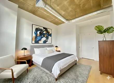 a bedroom with a bed a couch and potted plant on the table