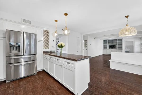 a kitchen with stainless steel appliances granite countertop a refrigerator a stove and a wooden floors