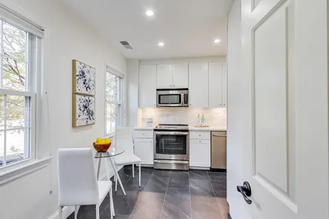 a kitchen with stainless steel appliances a stove a sink cabinets and a window