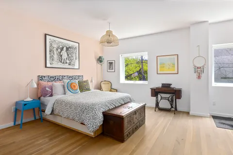 a bedroom with a bed painting on wall and a window