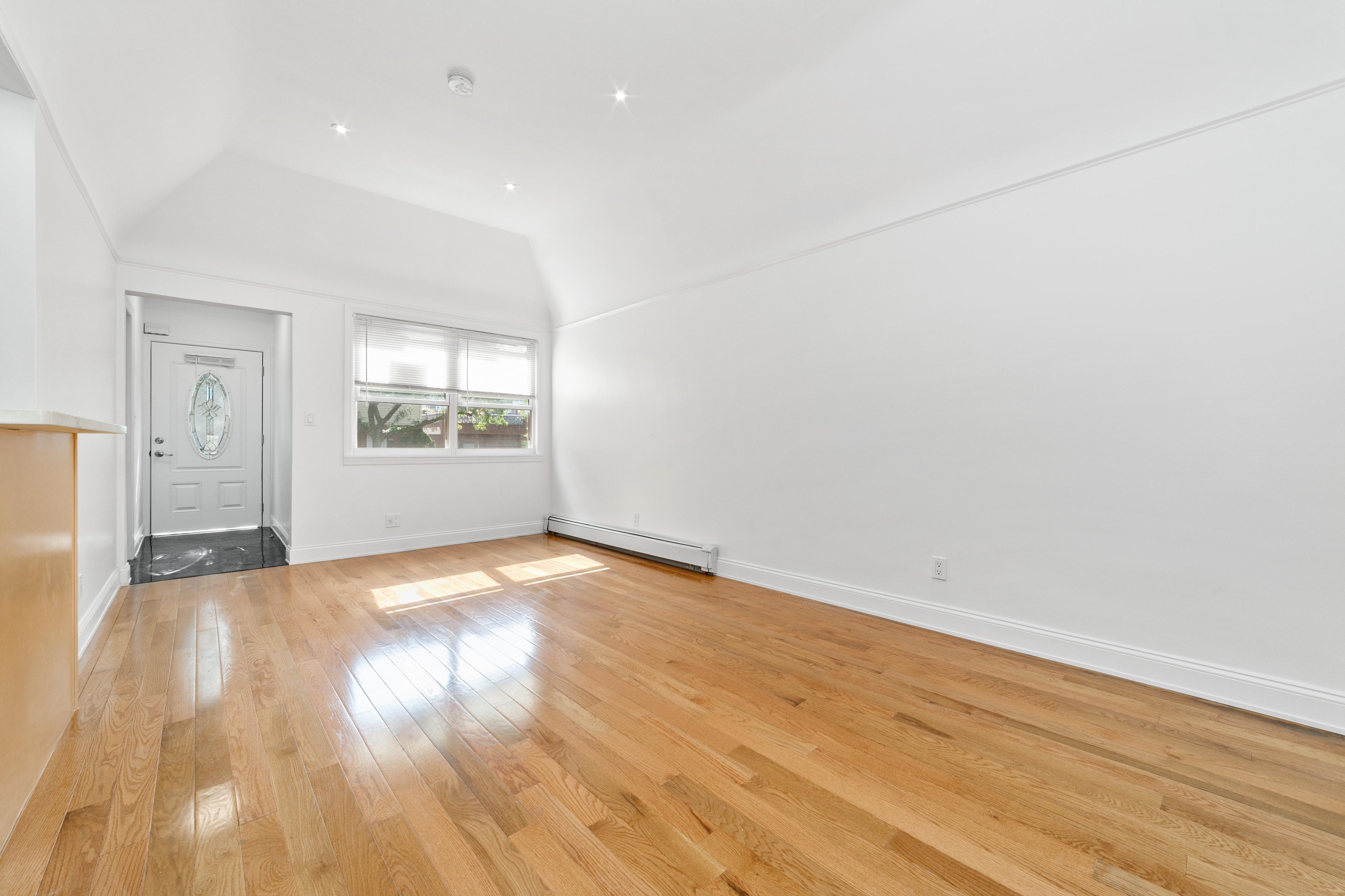 24-41 82nd Street Queens, NY 11370 - Photo 4 of 15 an empty room with wooden floor and windows