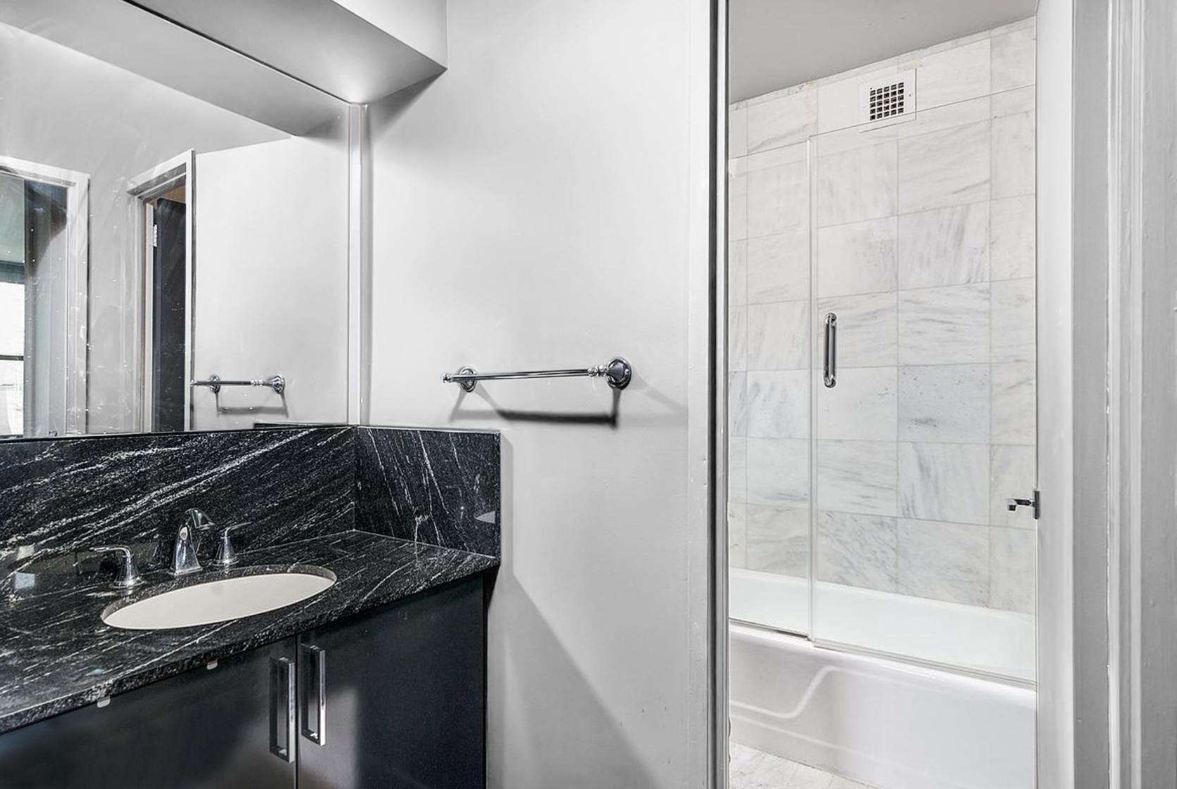 117 East 57th Street, Unit 48G Manhattan, NY 10022 - Photo 6 of 13 a bathroom with a granite countertop sink and a mirror