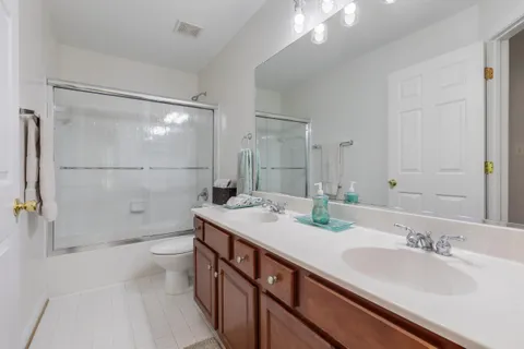 a bathroom with a double vanity sink toilet and shower
