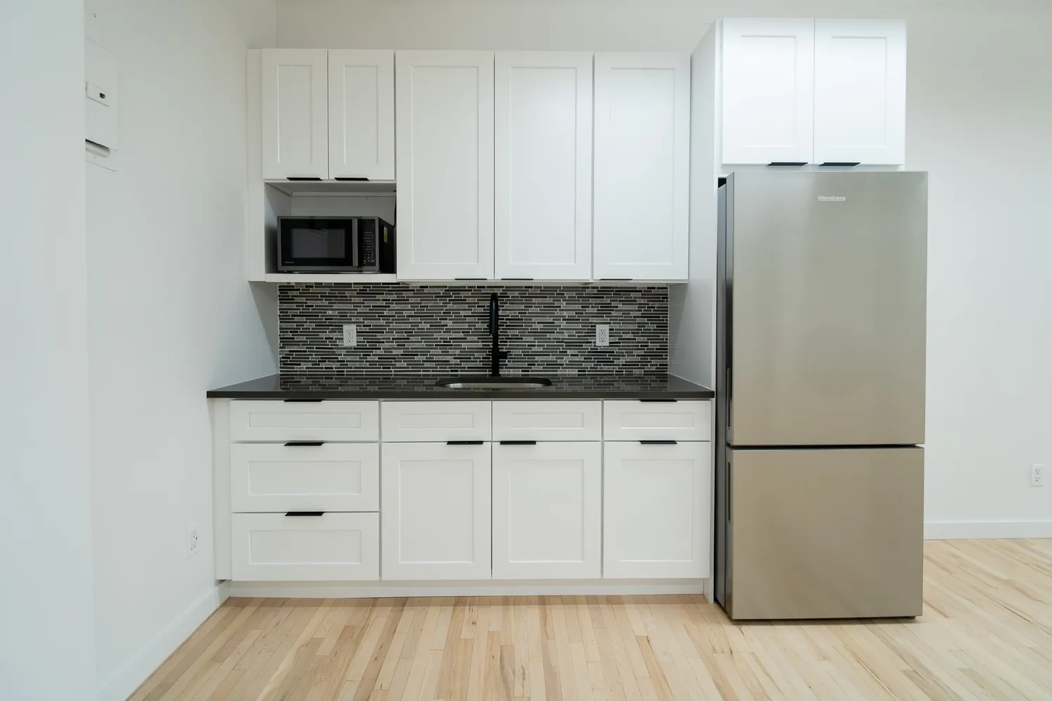 a kitchen with white cabinets and refrigerator