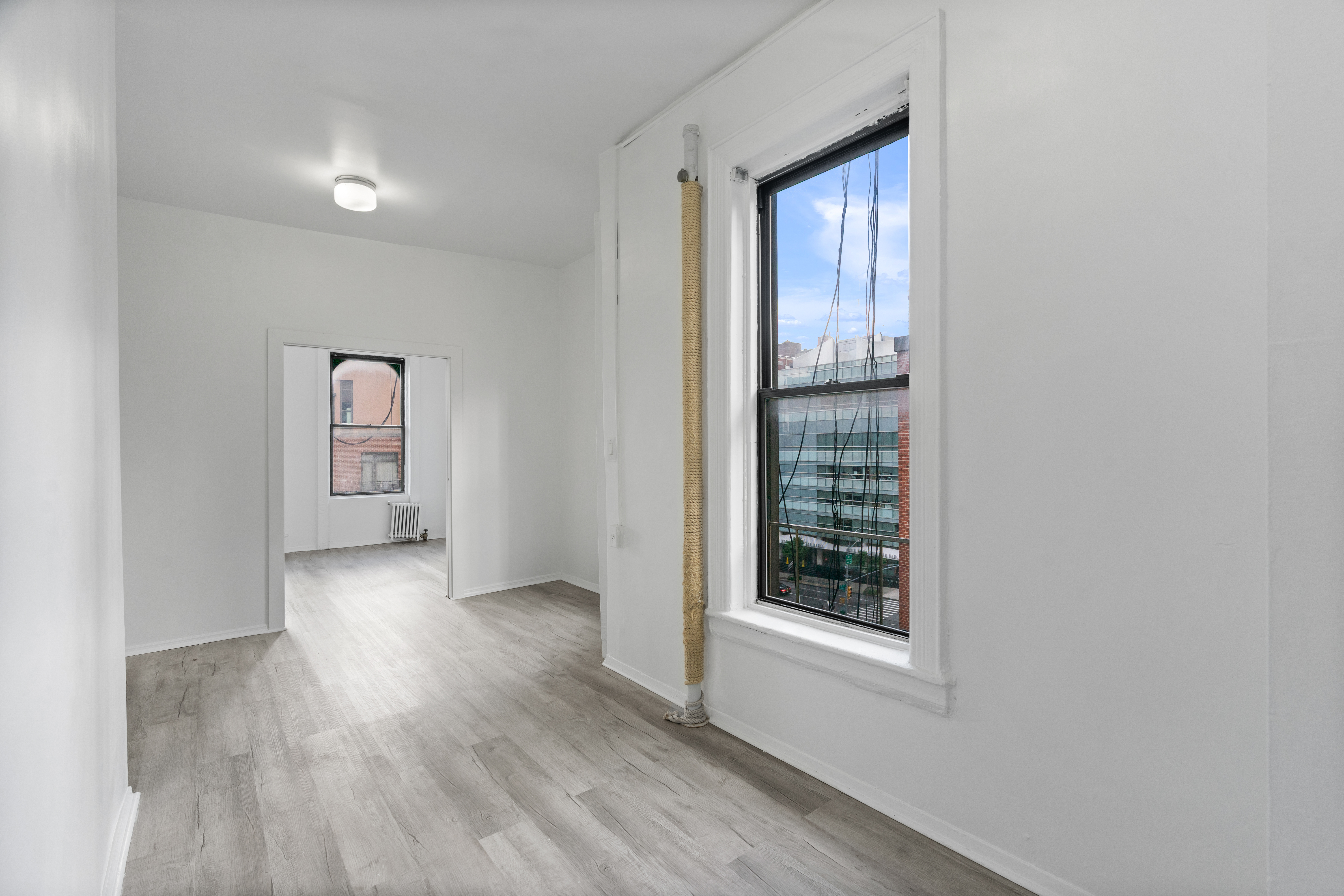 826 9th Avenue, Unit 5RS Manhattan, NY 10019 - Photo 7 of 15 a view of an empty room with window and wooden floor