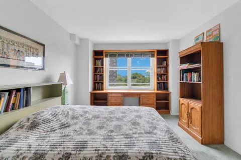 a bedroom with a bed dresser and a large window