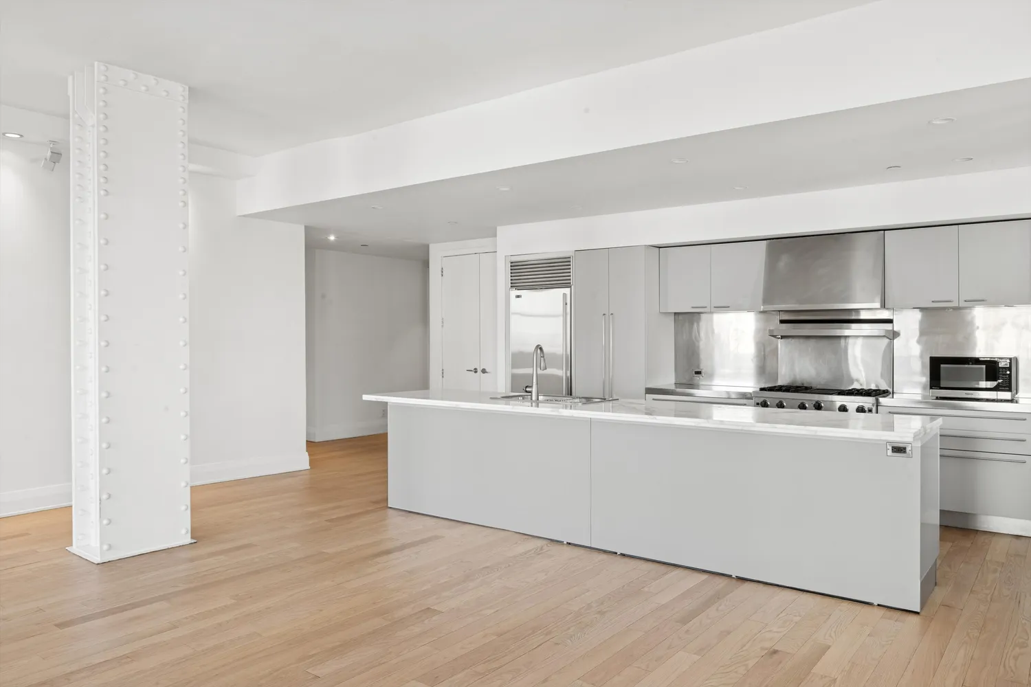 a view of kitchen with stainless steel appliances a sink and wooden floor