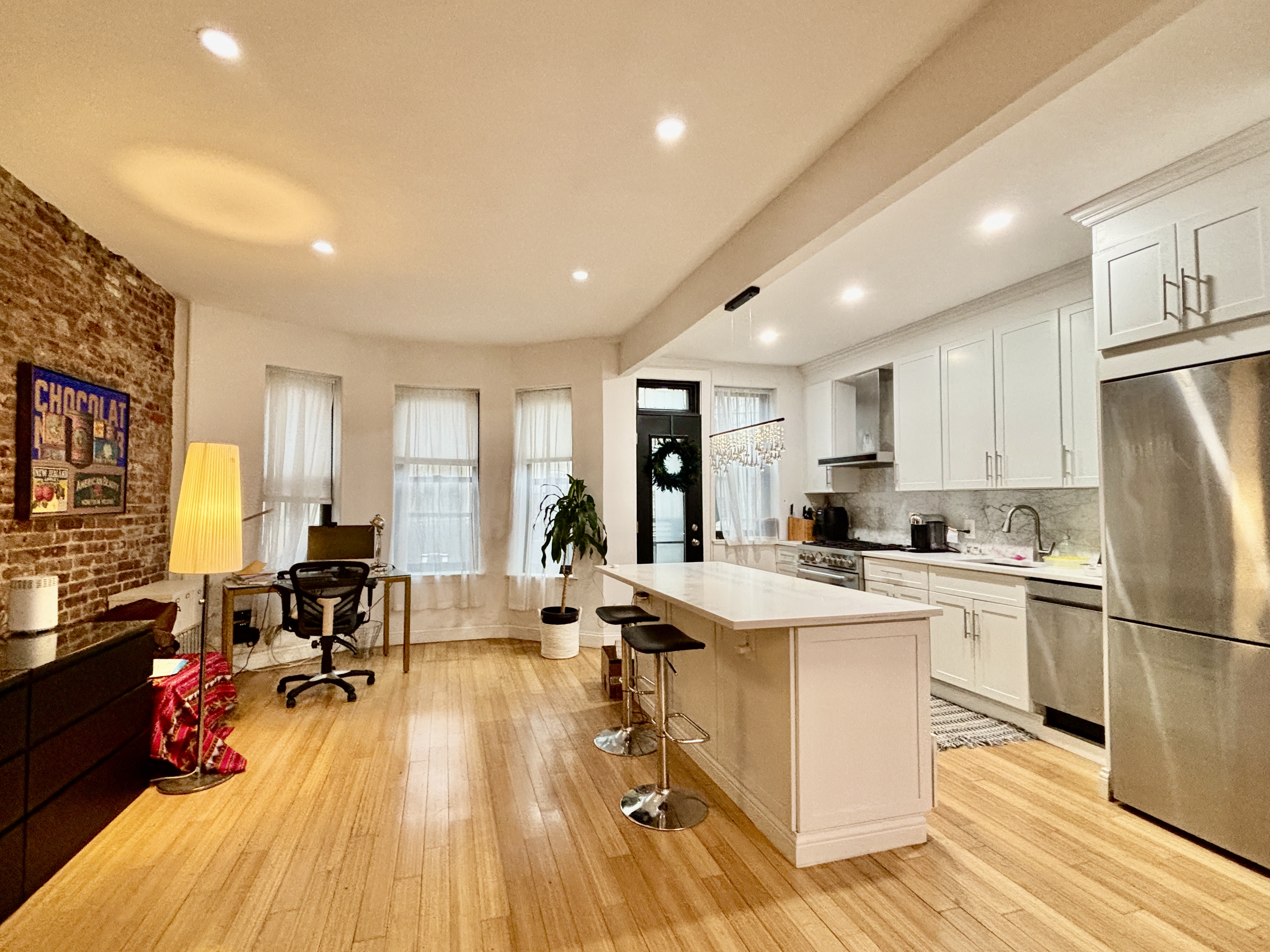848 Macon Street, Unit PARLOR Brooklyn, NY 11233 - Photo 5 of 10 a kitchen with a refrigerator a stove cabinets dining table and chairs with wooden floor