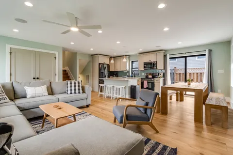 a living room with furniture wooden floor and a kitchen view