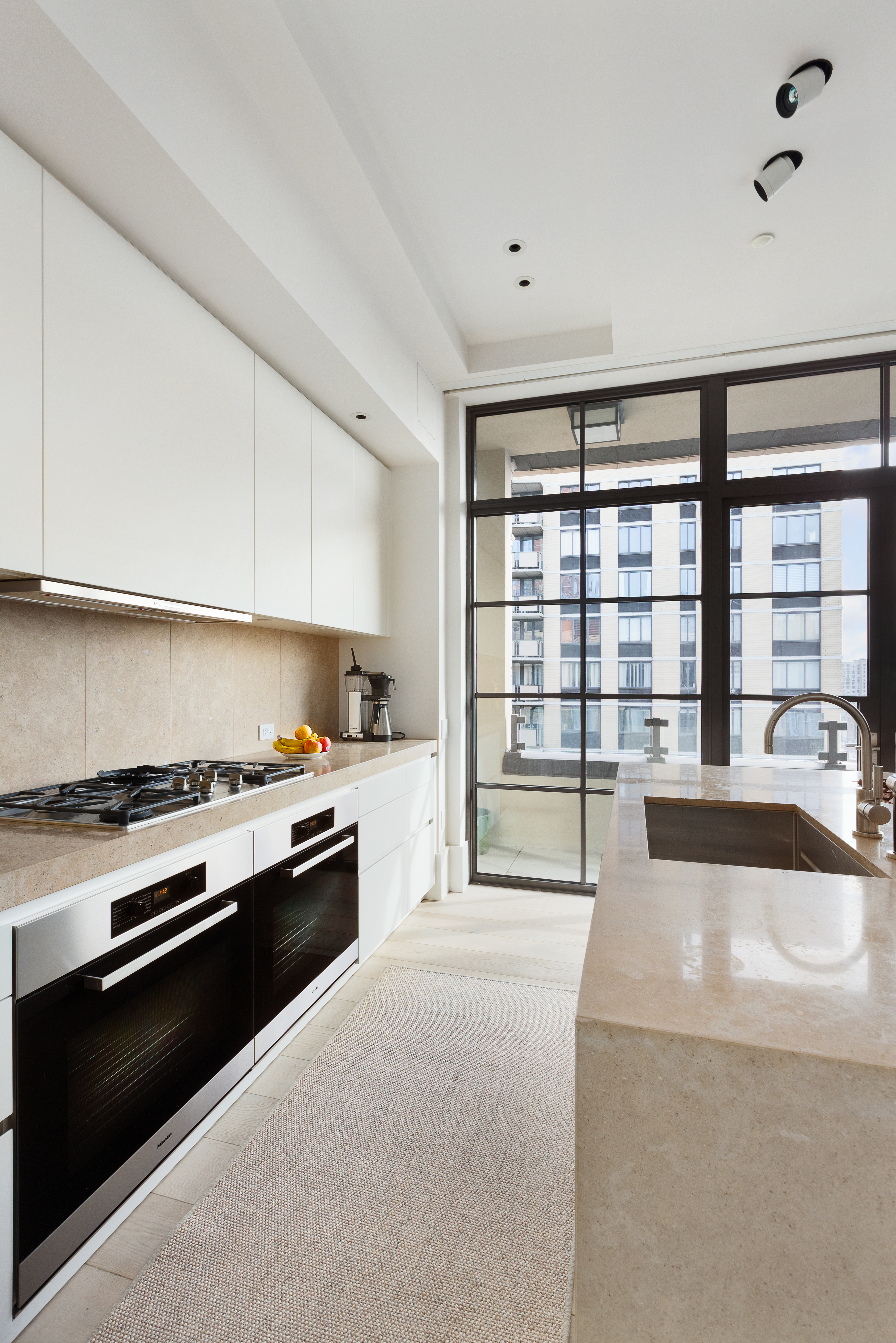 404 Park Avenue South, Unit PH17A Manhattan, NY 10016 - Photo 3 of 9 a large white kitchen with granite countertop a stove top oven a sink and dishwasher