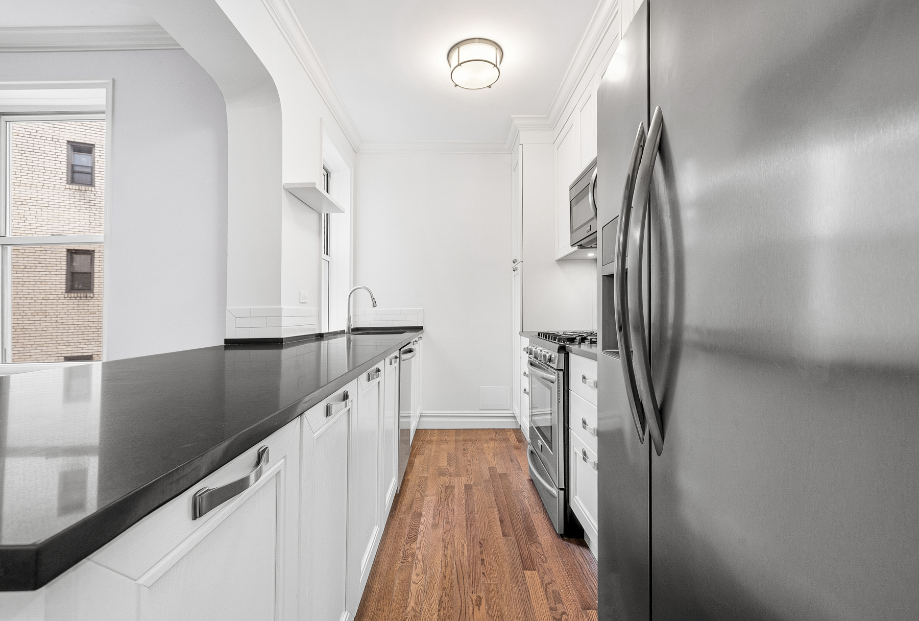 73-12 35th Avenue, Unit D56 Queens, NY 11372 - Photo 4 of 15 a view of a kitchen with a sink and wooden floor