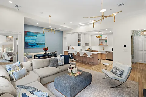 a living room with furniture kitchen view and a chandelier