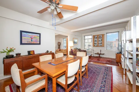 a dining room with wooden floor a chandelier fan a wooden table and chairs