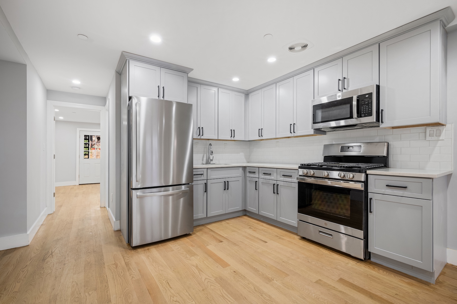 307 West 136th Street Manhattan, NY 10030 - Photo 18 of 26 a kitchen with stainless steel appliances granite countertop a refrigerator oven a sink dishwasher and white cabinets with wooden floor