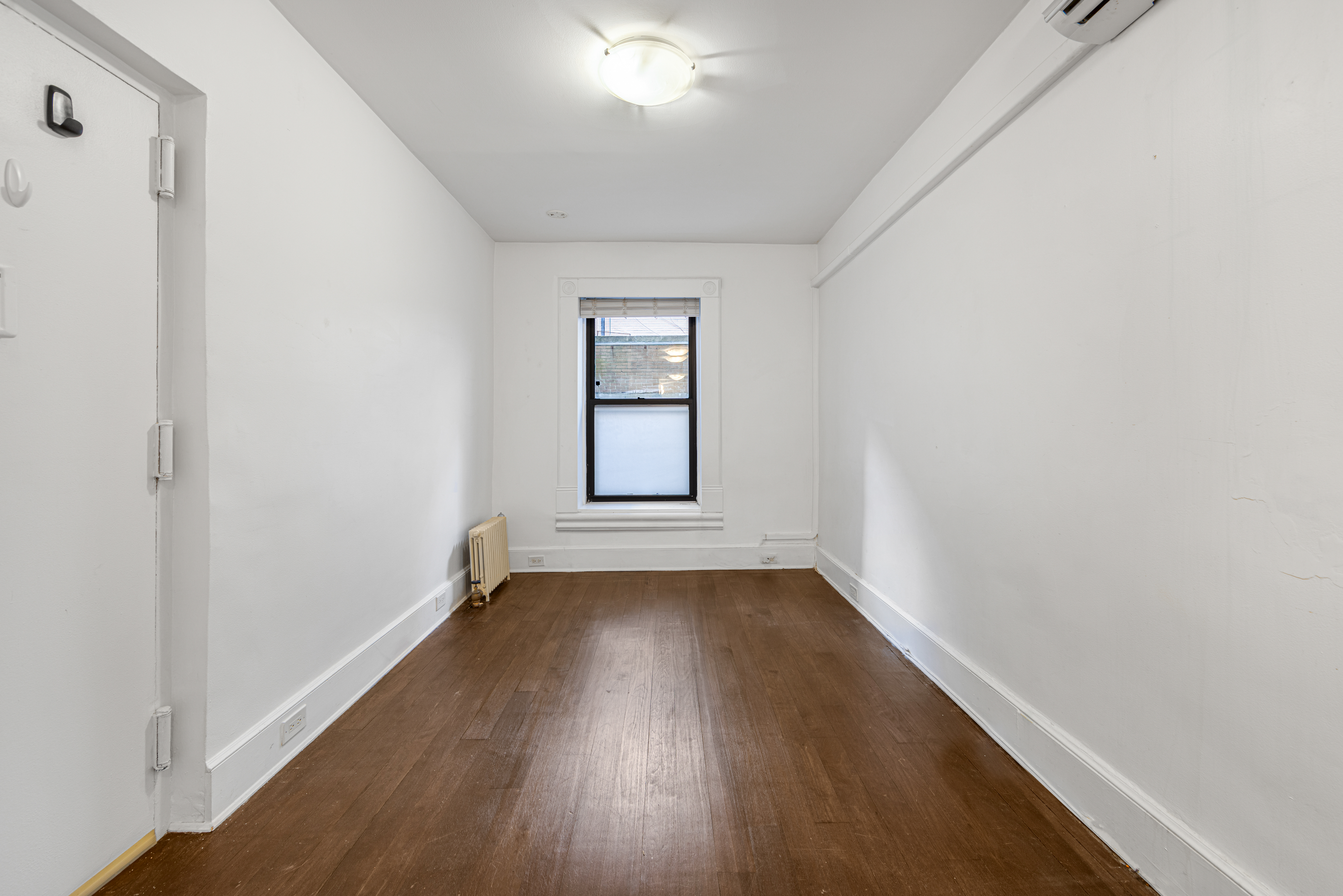 241 Mulberry Street, Unit 3 Manhattan, NY 10012 - Photo 6 of 8 an empty room with wooden floor and windows