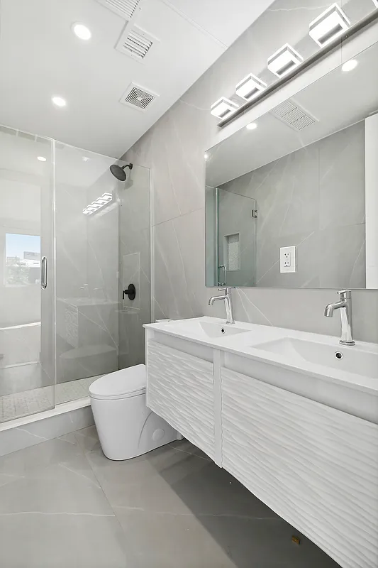 483 Hart Street, Unit PH Brooklyn, NY 11221 - Photo 8 of 17 a spacious bathroom with a double vanity sink a large mirror and shower