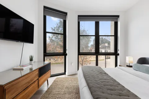 a bedroom with a large bed and a flat tv screen on dresser