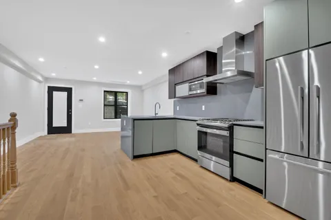 a kitchen with stainless steel appliances granite countertop a refrigerator a stove and a sink
