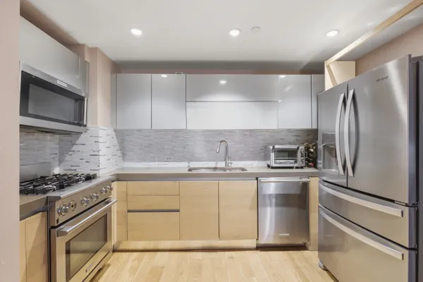 a kitchen with stainless steel appliances granite countertop a stove a refrigerator and a microwave