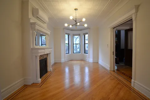 a view of an empty room with window and wooden floor