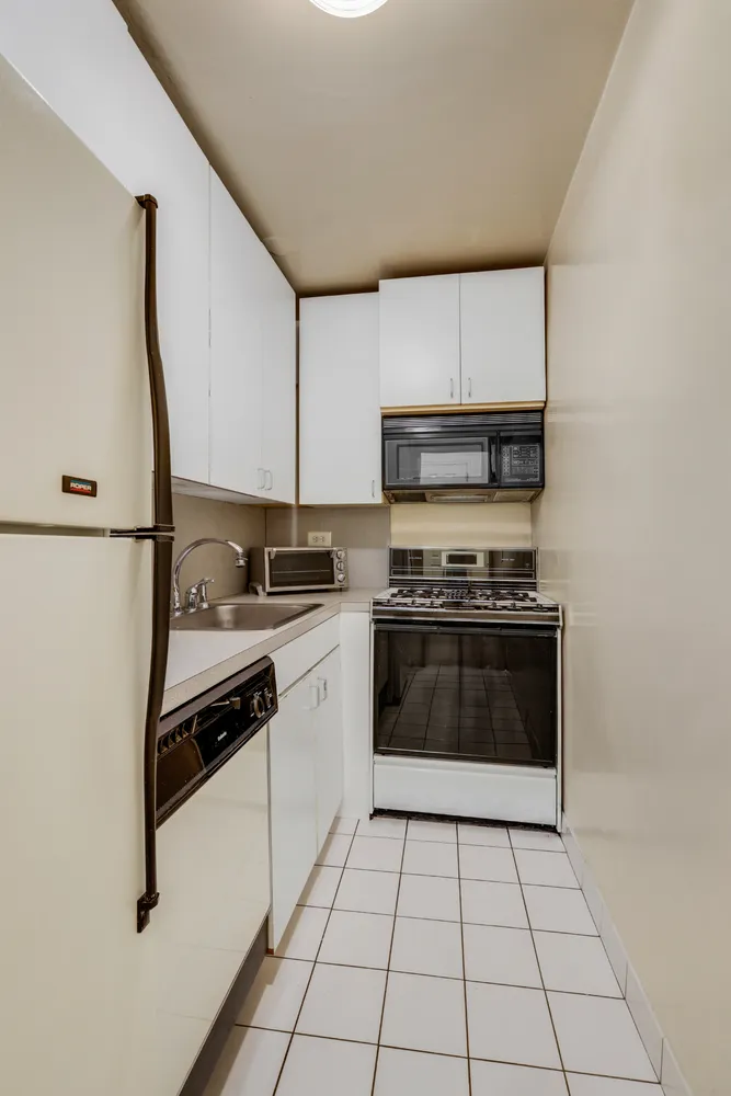 a kitchen with granite countertop a stove top oven and cabinets