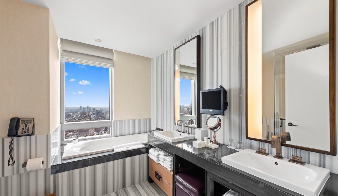 246 Spring Street, Unit 4103 Manhattan, NY 10013 - Photo 5 of 20 a bathroom with a double vanity sink a mirror and a bathtub