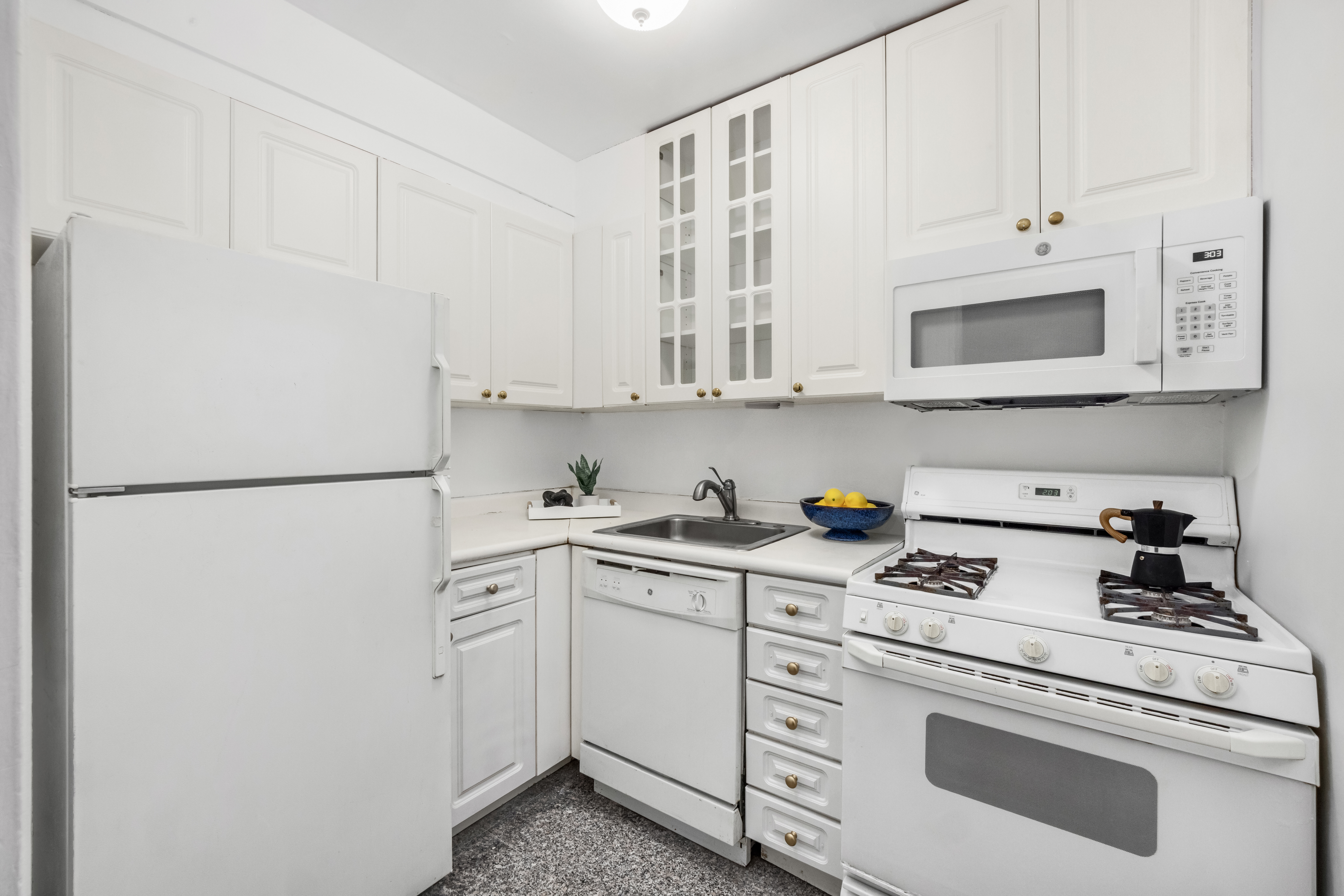 200 East 58th Street, Unit 6B Manhattan, NY 10022 - Photo 7 of 12 a kitchen with white cabinets and white appliances